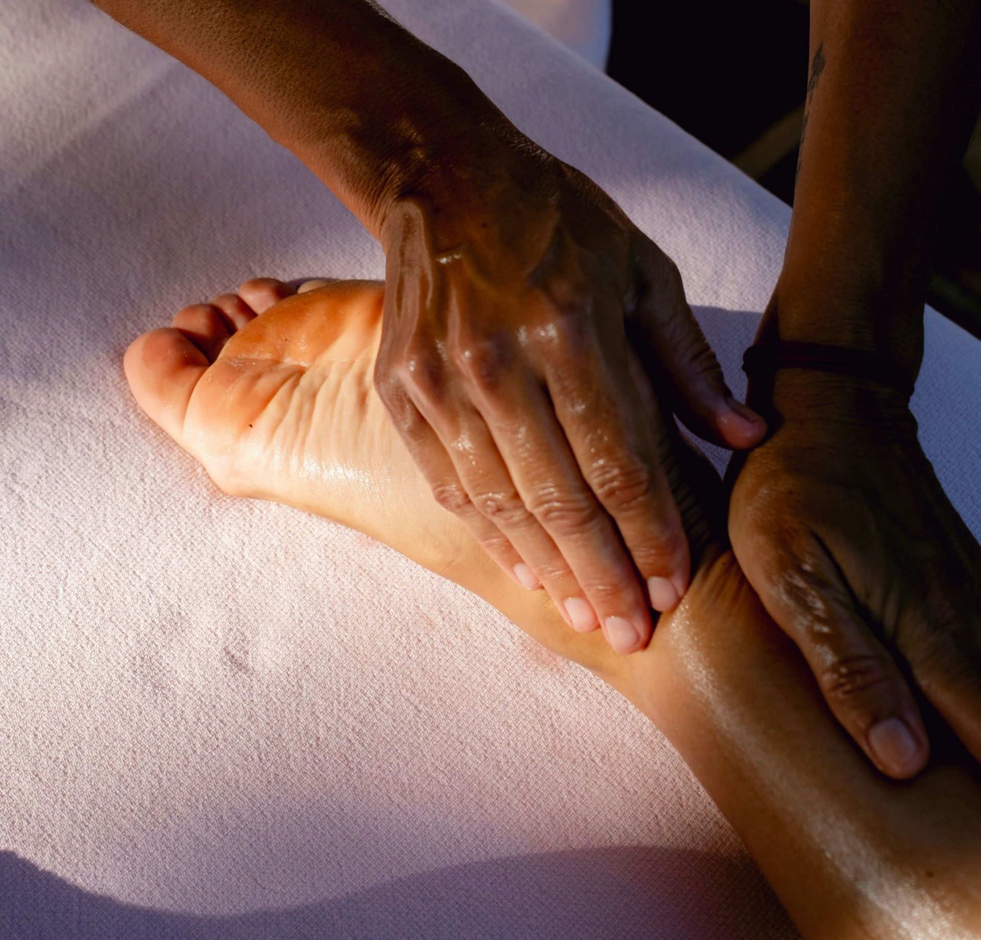 A person is doing a foot massage on a bed
